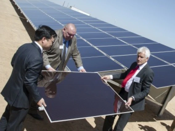 3 men. moving a solar panel towards a solar array