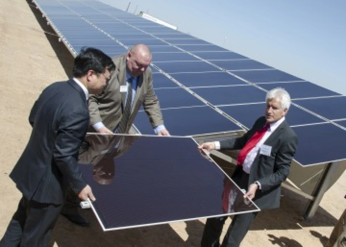 3 men. moving a solar panel towards a solar array